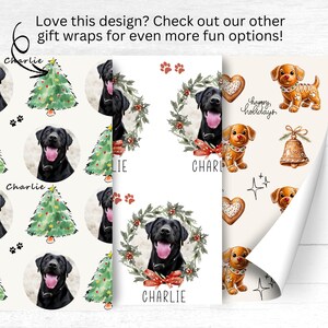 Pode incluir: Papel de embrulho com um Labrador Retriever preto, &aacute;rvores de Natal, grinaldas e desenhos de cachorros. O papel inclui o nome "Charlie" e o texto "Happy Holidays".
