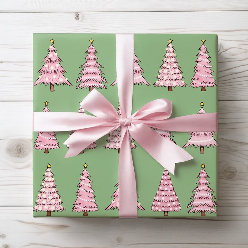 May include: A wrapped gift with green wrapping paper featuring a repeating pattern of pink Christmas trees with yellow star toppers. A light pink satin ribbon is tied in a bow around the gift.