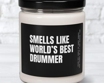 May include: A white candle with a black label that reads "Smells Like World's Best Drummer".