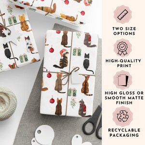 K&ouml;nnte beinhalten: Verpackte Geschenke mit Geschenkpapier zum Thema Katze. Das Papier zeigt Aquarellillustrationen von Katzen, Weihnachtsschmuck und Geschenkboxen. Die Geschenke sind mit Bindfaden und einem leeren Anh&auml;nger gebunden. Der Text sagt "TWO SIZE OPTIONS", "HIGH-QUALITY PRINT", "HIGH GLOSS OR SMOOTH MATTE FINISH" und "RECYCLABLE PACKAGING".