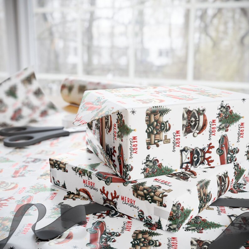 May include: Two wrapped gifts with white wrapping paper featuring a repeating pattern of raccoons, Christmas trees, and red cars. The words "MERRY CHRISTMAS" are printed on the paper. A pair of scissors and a roll of wrapping paper are in the background.