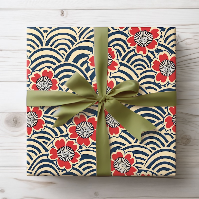 Puede incluir: Un regalo envuelto en papel con un estampado de flores rojas y dise&ntilde;os de olas azul marino sobre un fondo crema. Est&aacute; atado con una cinta y lazo de sat&eacute;n verde, ideal para ocasiones especiales.