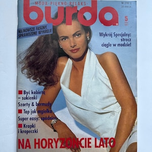 Op de afbeelding: Een vintage magazine cover met een vrouw in een witte haltertop. De magazine titel "burda" staat in grote rode letters. Tekst bevat "NAJNOWSZE FASONY, SPRAWDZONE WYKROJE" en "NA HORYZONCIE LATO".