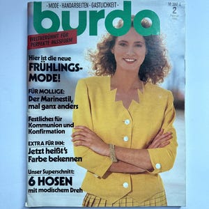 Op de afbeelding: Een tijdschriftcover met de titel "burda" in het groen. De cover toont een vrouw in een gele blazer. Tekst bevat "Lentemode" en "6 Broeken". Het tijdschrift heeft een vintage ontwerp.