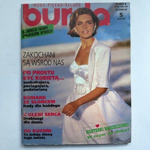 Op de afbeelding: Een vintage magazine cover met een vrouw in een witte jurk en jasje. De tijdschrifttitel is "burda" in rode letters. De cover bevat Poolse tekst en het nummer "5" met de datum "mei'92".