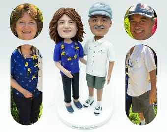 Puede incluir: Una figura personalizada de una pareja, la mujer lleva una camisa azul con un collar de flores y el hombre lleva una camisa blanca y pantalones cortos de color caqui. La figura está de pie sobre una base blanca con el texto "Happy 40th Anniversary" escrito en ella.
