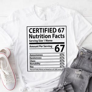 May include: White t-shirt featuring a black graphic designed as a nutrition facts label. The label humorously lists "Awesomeness" and "Rizz" at 67%. The text reads "CERTIFIED 67 Nutrition Facts". The shirt is displayed with jeans and white trainers.