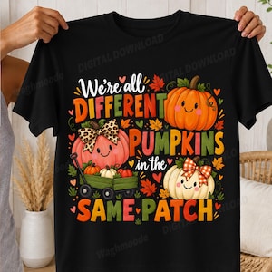 Könnte beinhalten: Ein schwarzes T-Shirt mit einem Aufdruck, der den Text "We're all DIFFERENT PUMPKINS in the SAME PATCH" zeigt. Das Design umfasst drei lächelnde Kürbisse, einer davon in einem grünen Wagen, verziert mit einer Leopardenmuster-Schleife und einer rot-karierten Schleife, umgeben von Herbstblättern.