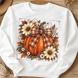 Könnte beinhalten: Ein weißes Langarm-Sweatshirt mit einem zentralen Motiv aus einem großen orangefarbenen Kürbis, der mit einer karierten Schleife verziert ist und von Sonnenblumen, Herbstblättern und roten Beeren umgeben ist, eingerahmt von einem dünnen schwarzen Rand.