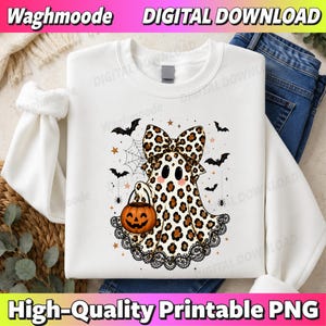 Könnte beinhalten: Ein weißes Sweatshirt mit einer Grafik eines Geistes mit Leopardenmuster, einer großen passenden Schleife und rosa Wangen. Der Geist hält einen orangefarbenen Kürbiseimer. Das Design umfasst schwarze Spitzenborte, Fledermäuse, Sterne und ein Spinnennetz.