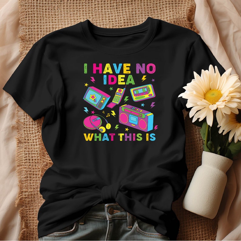 May include: Black t-shirt with a colorful graphic of retro electronics and the text "I have no idea what this is".