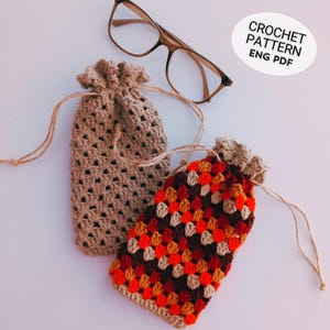 Könnte beinhalten: Zwei gehäkelte Kordelzugbeutel in Beige und ein farbenfrohes Patchworkmuster, mit einer Brille. Der beige Beutel ist einfarbig, während der andere rote, orangefarbene und braune Quadrate aufweist. Der Text "CROCHET PATTERN ENG PDF" befindet sich oben rechts.