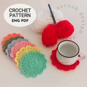 以下が含まれることがあります： フリルのある縁取りが施された、カラフルなクロシェコースター6枚セット。コースターは、一番大きなコースターが下、一番小さなコースターが上に積み重ねられています。コースターは、オレンジ、グリーン、グレー、ピンク、イエロー、グリーンなど、さまざまな色で作られています。コースターは白い表面の上に置かれています。画像には、赤い毛糸玉、白い毛糸玉、かぎ針も写っています。