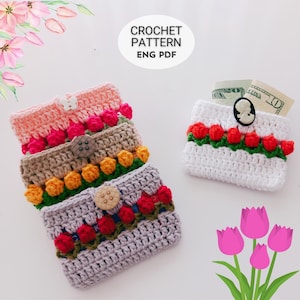 Puede incluir: Carteras de ganchillo en varios colores, incluyendo rosa, beige y gris, adornadas con diseños de tulipanes coloridos. Cada cartera tiene un cierre de botón. Una cartera blanca contiene dinero en efectivo y está decorada con tulipanes rojos y un botón de cameo. El texto "CROCHET PATTERN ENG PDF" es visible.