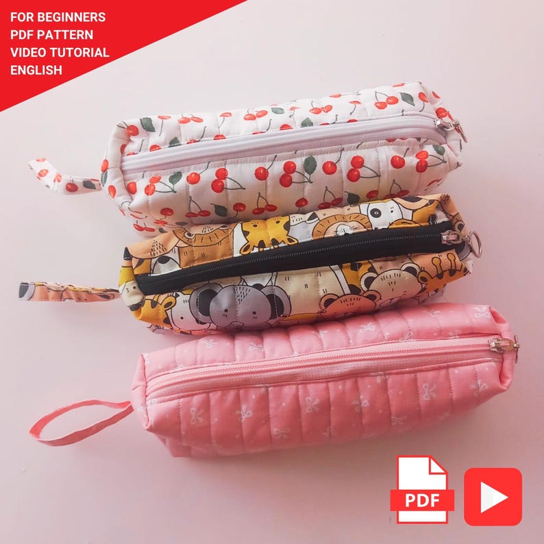 May include: Three quilted pencil cases in a stack. The top case has a white background with red cherries. The middle case has a tan background with animal illustrations. The bottom case is pink with a floral pattern. The text "FOR BEGINNERS PDF PATTERN VIDEO TUTORIAL ENGLISH" is in the top left corner.