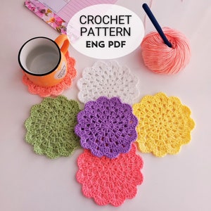 May include: Six crocheted coasters in different colors, including white, green, purple, yellow, and pink. The coasters are arranged in a circle on a white surface. The text "CROCHET PATTERN ENG PDF" is visible in the image.