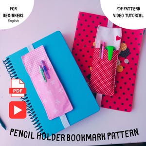 Könnte beinhalten: Zwei Notizbücher mit Stifthalter-Lesezeichen. Eines ist blau, das andere rot mit schwarzen Punkten. Die Stifthalter sind rosa und rot mit weißen Akzenten. Der Text auf dem Bild lautet "PENCIL HOLDER BOOKMARK PATTERN" und "PDF PATTERN VIDEO TUTORIAL".