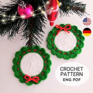 Puede incluir: Dos posavasos circulares de ganchillo con un centro blanco rodeado por un borde verde festoneado con costuras rojas y un pequeño lazo rojo. El texto CROCHET PATTERN ENG PDF es visible en la esquina inferior derecha de la imagen.