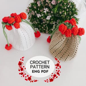 Puede incluir: Se muestran dos bolsas de crochet con cordón, una blanca y otra beige. Cada bolsa está adornada con un grupo de flores rojas de ganchillo y detalles verdes. Las bolsas tienen un aspecto texturizado y están sobre un fondo floral. También se ve el texto "CROCHET PATTERN ENG PDF".