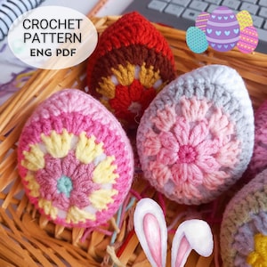 May include: Crochet Easter egg patterns in pink, red, and grey with floral designs. The pattern is available in English PDF format. CROCHET PATTERN ENG PDF