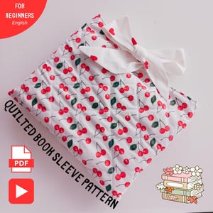 May include: A quilted book sleeve pattern featuring a white background adorned with a pattern of red cherries and green leaves. The sleeve is tied with a white bow. Text on the image reads "Quilted Book Sleeve Pattern" and "For Beginners English".