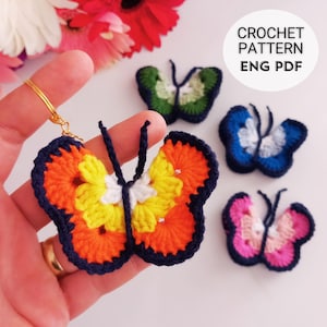 May include: A handmade crochet butterfly keychain in orange, yellow, and white, with a navy blue border. The image also shows three other crochet butterflies in green, blue, and pink. Text on the image reads "CROCHET PATTERN ENG PDF".