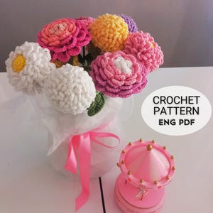 May include: A bouquet of handmade crochet flowers in a white vase tied with a pink ribbon. The flowers are various colors, including white, pink, yellow, and purple. The text "CROCHET PATTERN ENG PDF" is visible.