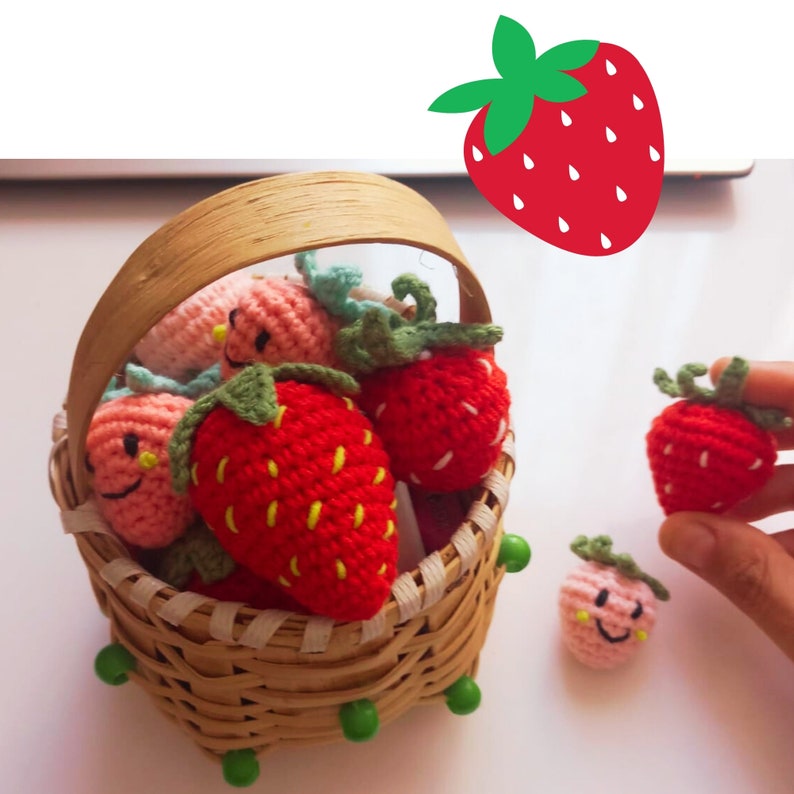 May include: A small woven basket filled with crocheted strawberries. The strawberries are red with green tops and yellow detailing. Some have smiling faces. A single strawberry is held in a hand, and a strawberry graphic is in the background.