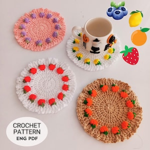 以下が含まれることがあります： 異なる色の糸とフルーツのデザインが施された、4つのクロシェ編みコースター。コースターは白、ピンク、茶色、ベージュ。フルーツのデザインには、イチゴ、レモン、ブルーベリーが含まれています。