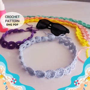 Può includere: Una collezione di fasce per capelli all'uncinetto colorate in varie tonalità, tra cui viola, azzurro, giallo e rosa. Occhiali da sole neri su una superficie bianca. È presente anche il testo "CROCHET PATTERN ENG PDF".