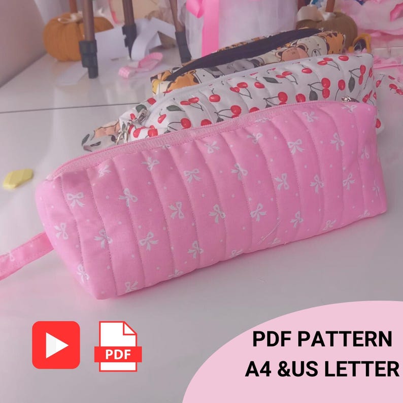 May include: Pink quilted pencil case with white bow pattern. The pencil case has a zipper closure and a small fabric loop. Other pencil cases with cherry and animal patterns are visible in the background. The image includes the text "PDF PATTERN A4 & US LETTER".