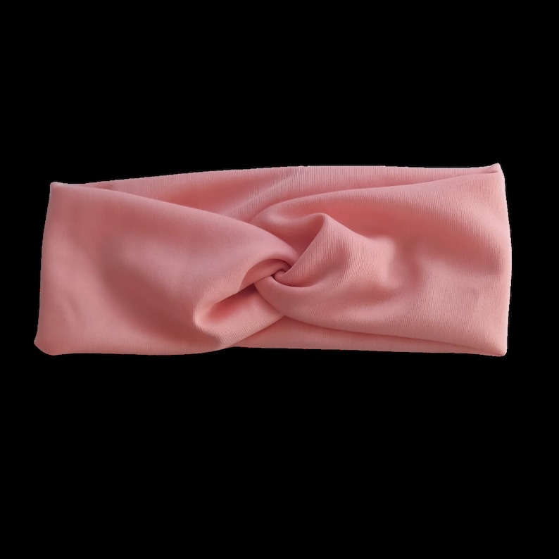 May include: A pink stretchy headband with a twisted knot design.