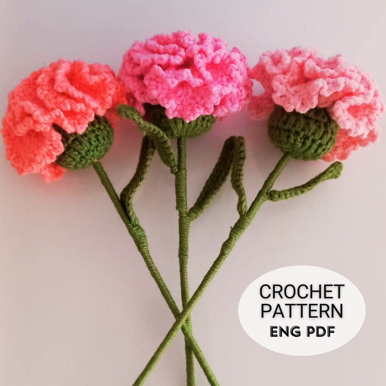 May include: Three crocheted carnation flowers in pink and coral with green stems and leaves. Crochet pattern ENG PDF.