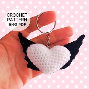 May include: White crocheted heart with black crocheted wings attached to a silver key chain.  Crochet pattern ENG PDF.