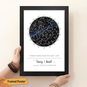 May include: A framed poster with a black background and a white circle in the center. The circle shows a constellation map with the text "Under these stars we said "I do"" and the names "Larry & Janet" below. The date "12.24.2023" and the location "Seattle, Washington" are also included.