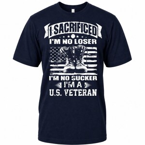May include: Navy blue t-shirt with a white graphic design. The design features combat boots in front of an American flag, with the text "I SACRIFICED I'M NO LOSER I'M NO SUCKER I'M A U.S. VETERAN."