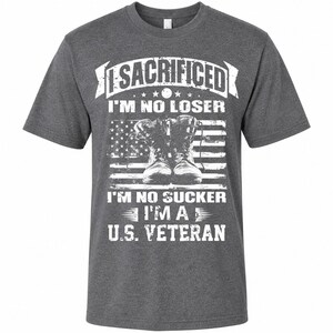 May include: Dark gray t-shirt with a graphic design. The design features the text "I SACRIFICED I'M NO LOSER I'M NO SUCKER I'M A U.S. VETERAN" in white, along with an American flag and combat boots.