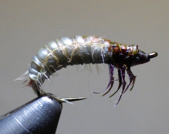 May include: A realistic fly fishing lure with a gray and brown body and purple legs.