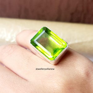 May include: A silver ring with a large, emerald-cut green gemstone.