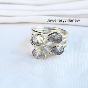 Può includere: Anello d'argento con tre pietre trasparenti a forma di goccia.
