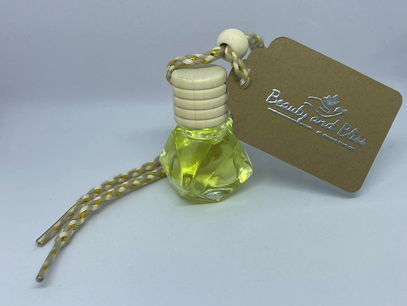 May include: A small, clear glass bottle containing a yellow liquid. The bottle has a wooden cap and a string with a tag that reads "Beauty and Bliss".
