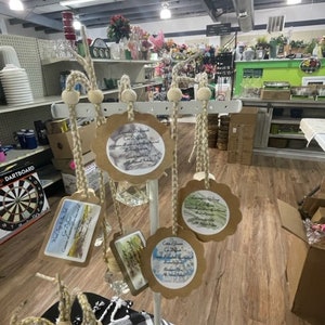 May include: A white metal stand with six brown paper tags hanging from it. Each tag has a different watercolour design and text. The tags are hanging from twine with wooden beads.