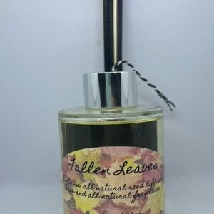 Peut inclure: Une bouteille en verre transparente avec un bouchon argent&eacute; et des roseaux noirs et blancs. La bouteille contient un liquide fonc&eacute; et porte une &eacute;tiquette sur laquelle est inscrit "Fallen Leaves" et "Beauty and Bliss All Natural Products".