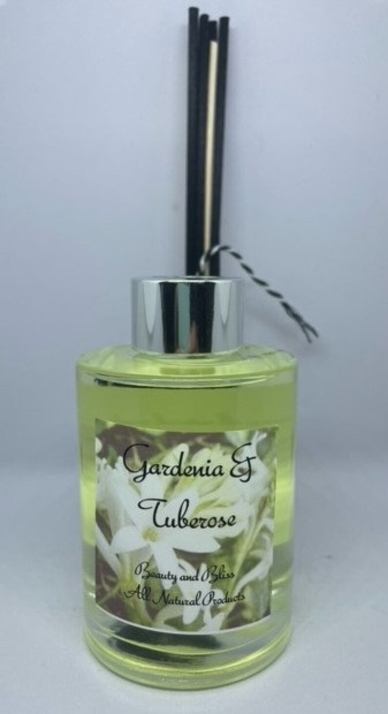 Peut inclure: Une bouteille en verre transparente avec un couvercle argent&eacute; et des roseaux noirs et blancs. La bouteille contient un liquide jaune et porte une &eacute;tiquette sur laquelle est &eacute;crit "Gardenia & Tuberose Beauty and Bliss All Natural Products".