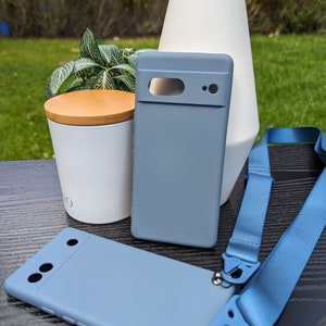 Pu&ograve; includere: Due custodie per telefono di colore azzurro chiaro con un laccio blu. Una custodia ha un ritaglio per la fotocamera e l'altra ha tre ritagli per la fotocamera.