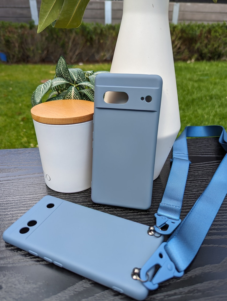 Pu&ograve; includere: Due custodie per telefono di colore azzurro chiaro con un laccio blu. Una custodia ha un ritaglio per la fotocamera e l'altra ha tre ritagli per la fotocamera.