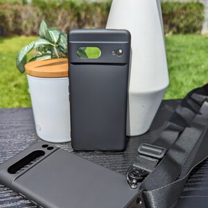 Pu&ograve; includere: Due custodie per telefono nere con un cinturino per telefono nero. Le custodie per telefono hanno un rialzo per la fotocamera rialzato e una finitura opaca liscia. Il cinturino ha una fibbia metallica e un gancio girevole.