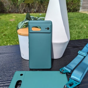 Pu&ograve; includere: Due custodie per telefono verde turchese con un laccio. Le custodie hanno un rialzo della fotocamera rialzato e una finitura liscia. Il laccio &egrave; blu e ha un clip su ciascuna estremit&agrave;.