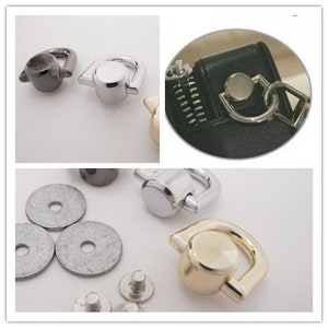 May include: An assortment of metal hardware components, including D-rings, washers, and rivets. The D-rings are in silver, gold, and gunmetal finishes. The image shows the hardware in various stages of assembly, with some attached to a black leather item.
