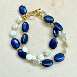 May include: A double-strand bracelet with oval-shaped lapis lazuli and white pearl beads separated by gold spacers.